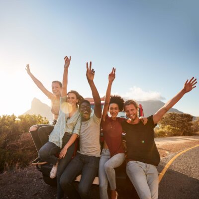 five people in the back of a parked truck raising their hands in celebration